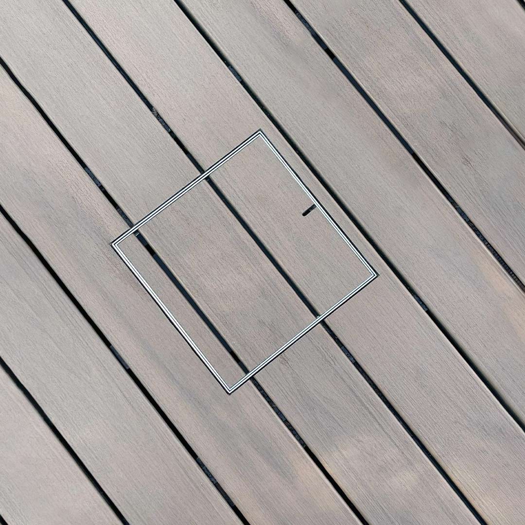 HIDE inlay access cover integrated into composite-style decking, maintaining uninterrupted board lines with a discreet lift point.