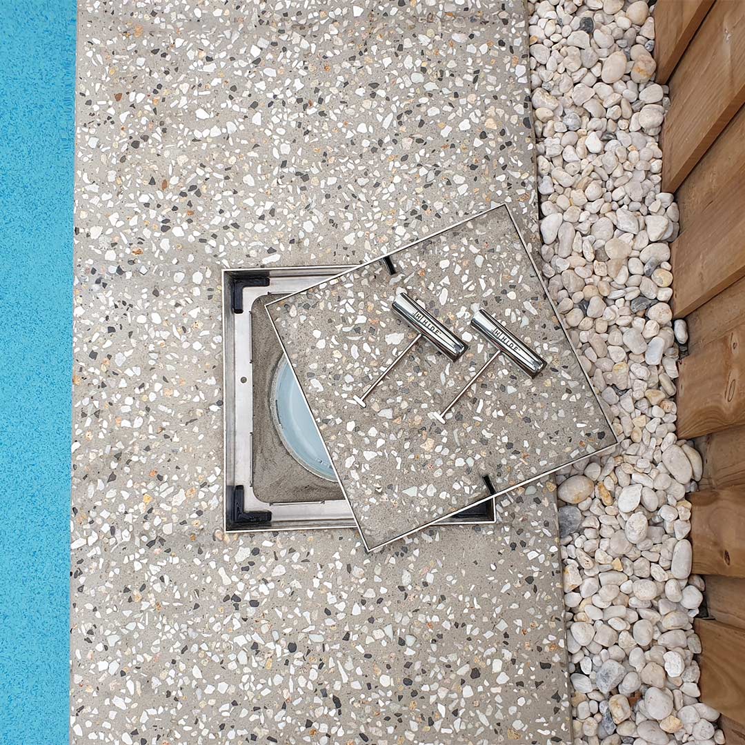 HIDE Concrete Skimmer Lid with exposed honed aggregate concrete infill. Installed next to swimming pool.
