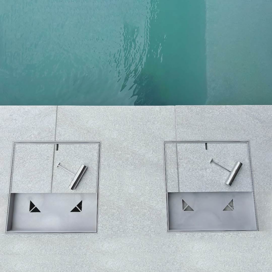 Two HIDE Ash Full Polymer Skimmer Lids installed flush in pool coping, providing a non-conductive, seamless poolside finish.