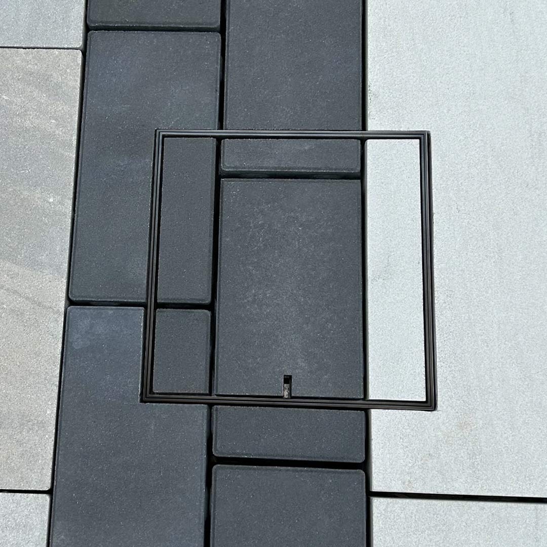 HIDE Charcoal Full Polymer Skimmer Lid installed flush within contrasting pavers, keeping the pattern crisp with a non-conductive, seamless finish.