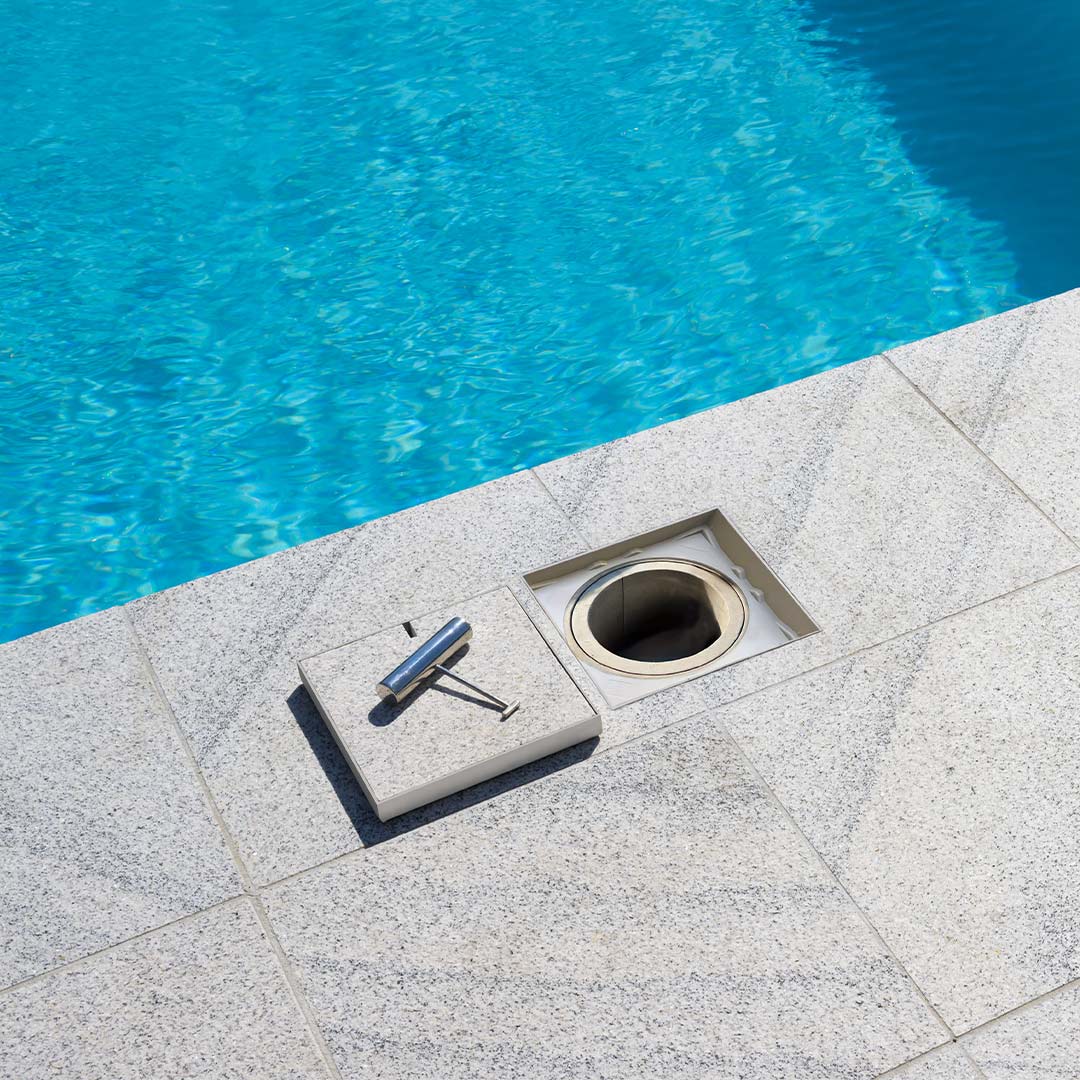 HIDE Ash Combination Polymer Access Cover with polymer non conductive frame and durable stainless steel lid sitting flush with surrounding tile around swimming pool.
