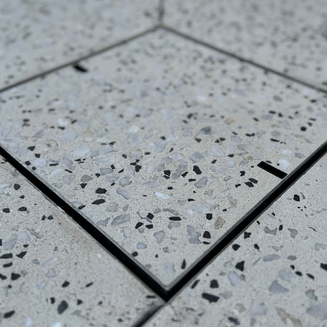 HIDE Concrete Drain Cover with aggregate wet-pour infill close up to see stainless steel edge protector and lid.