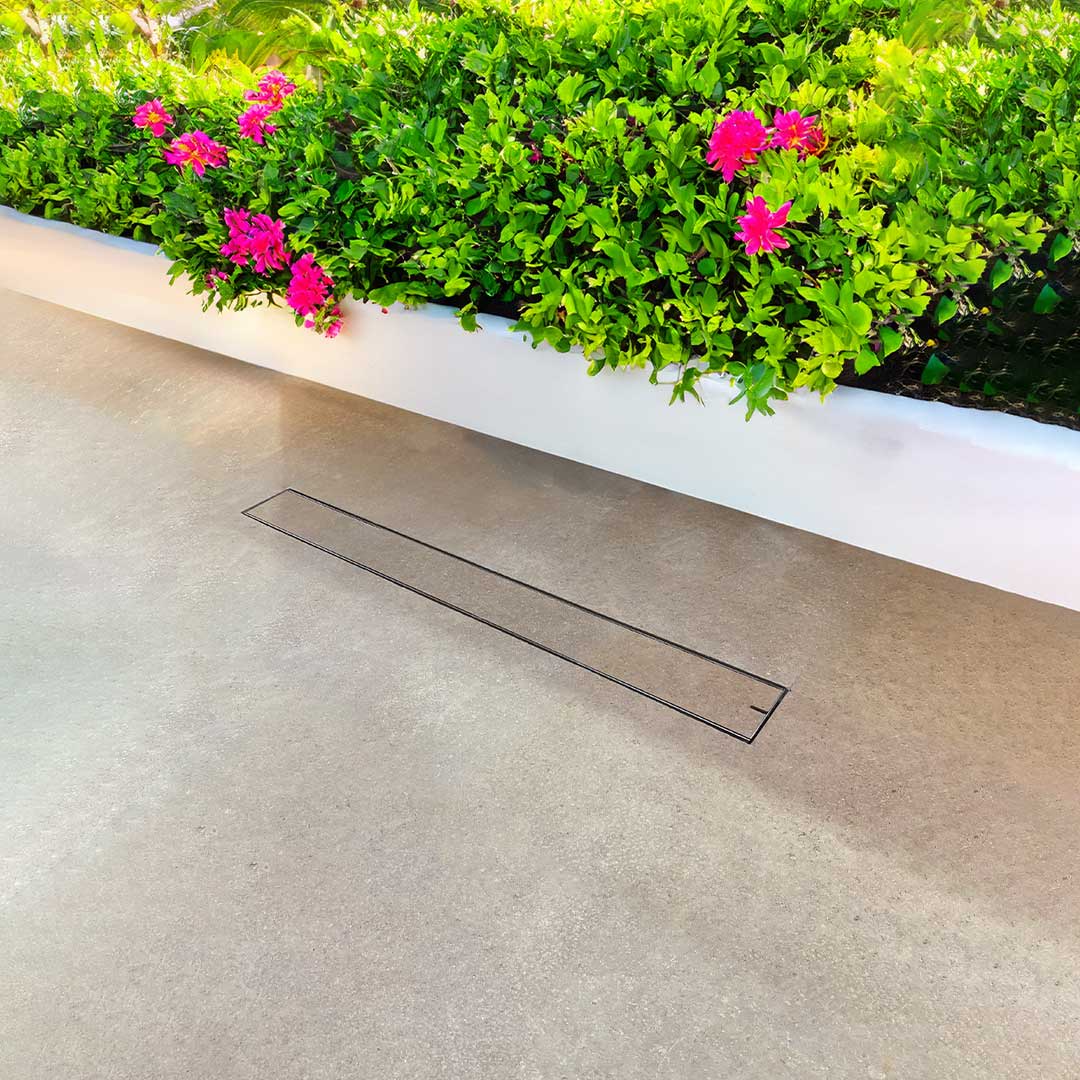 HIDE Concrete Linear Drain Cover installed next to retaining wall on patio.